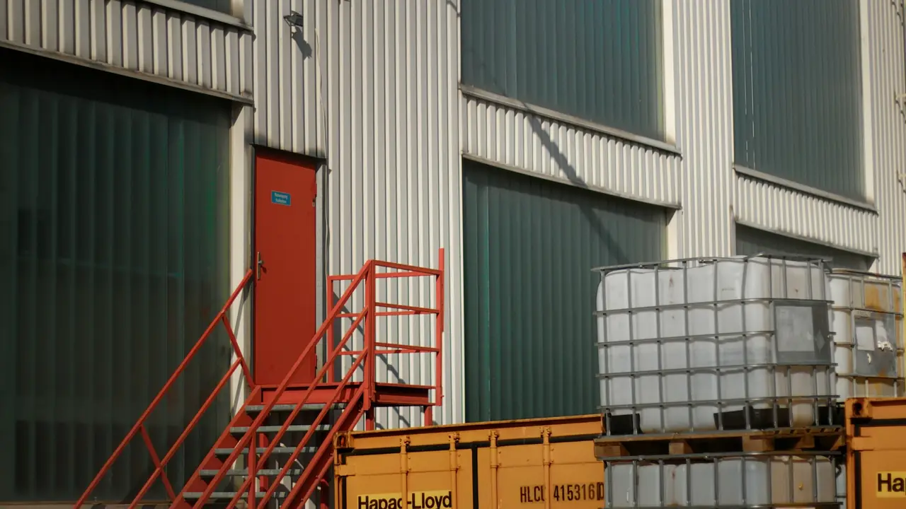 Nave industrial con contenedores y depósitos junto a la fachada
