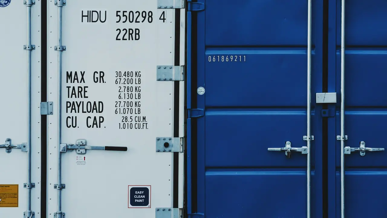 Puertas de dos contenedores, uno blanco y otro azul, con sus placas de datos