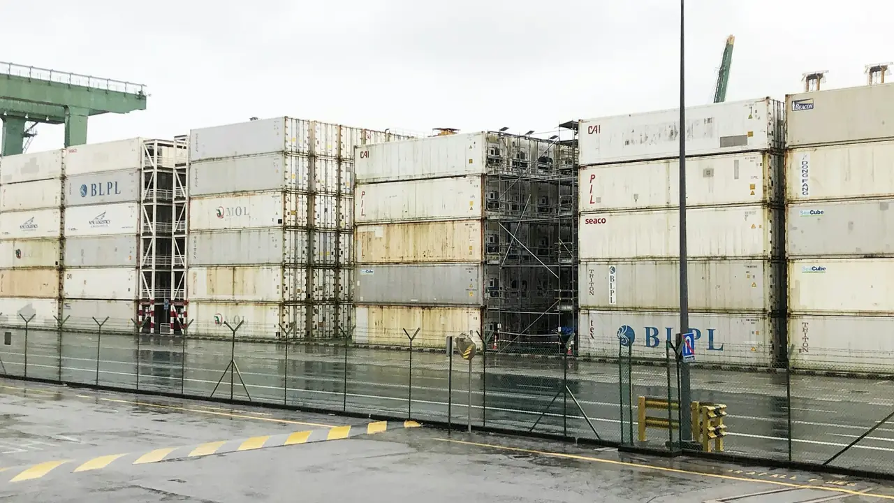 Fila de contenedores frigoríficos blancos apilados en un patio